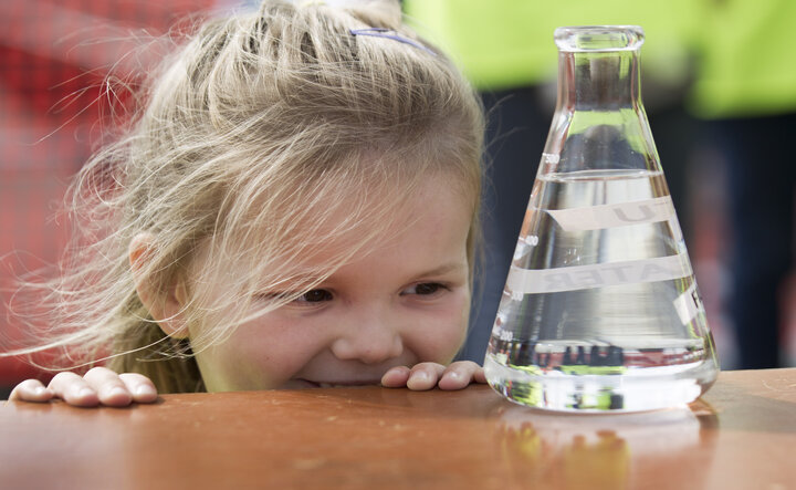 photo of a girl looking at a beaker or water